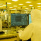 Shot of a Scientists in Sterile Suits Working with Computers, Analyzing Data form Modern Industrial Machinery in the Laboratory. Product Manufacturing Process: Pharmaceutics, Semiconductors, Biotechnology.