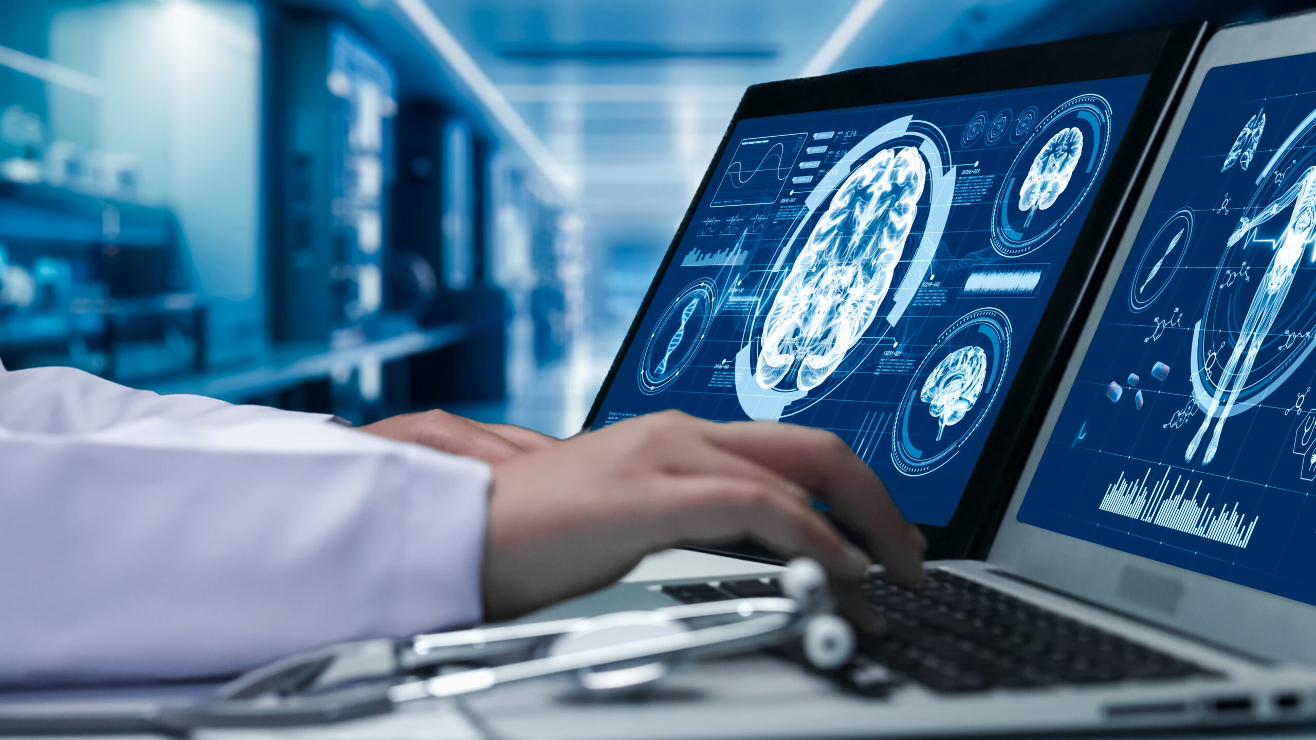 Close up of doctor working on tablet and laptop with human brain anatomy display on screen.